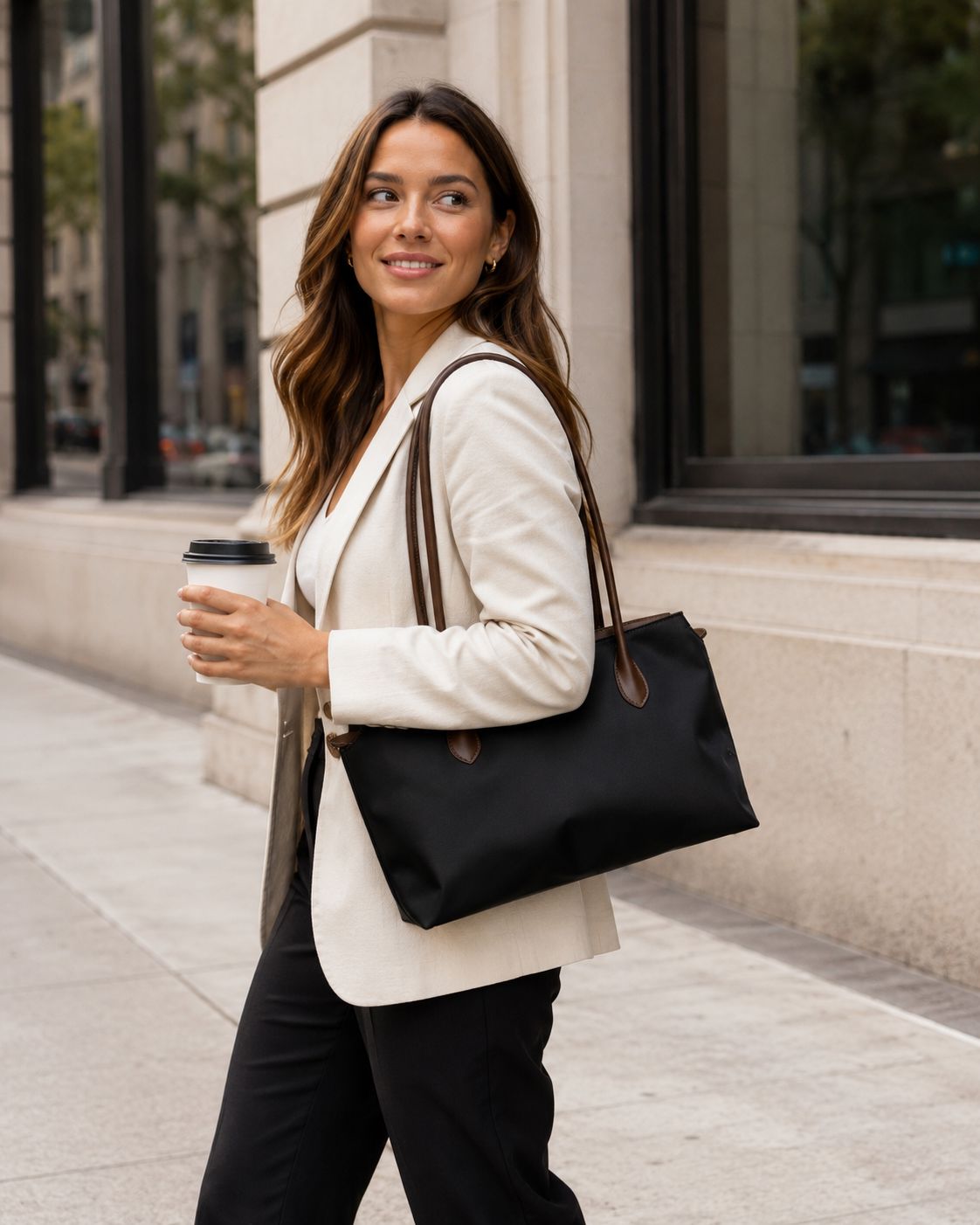 Layrich Woman carrying a lightweight black work tote during her city commute with coffee in hand